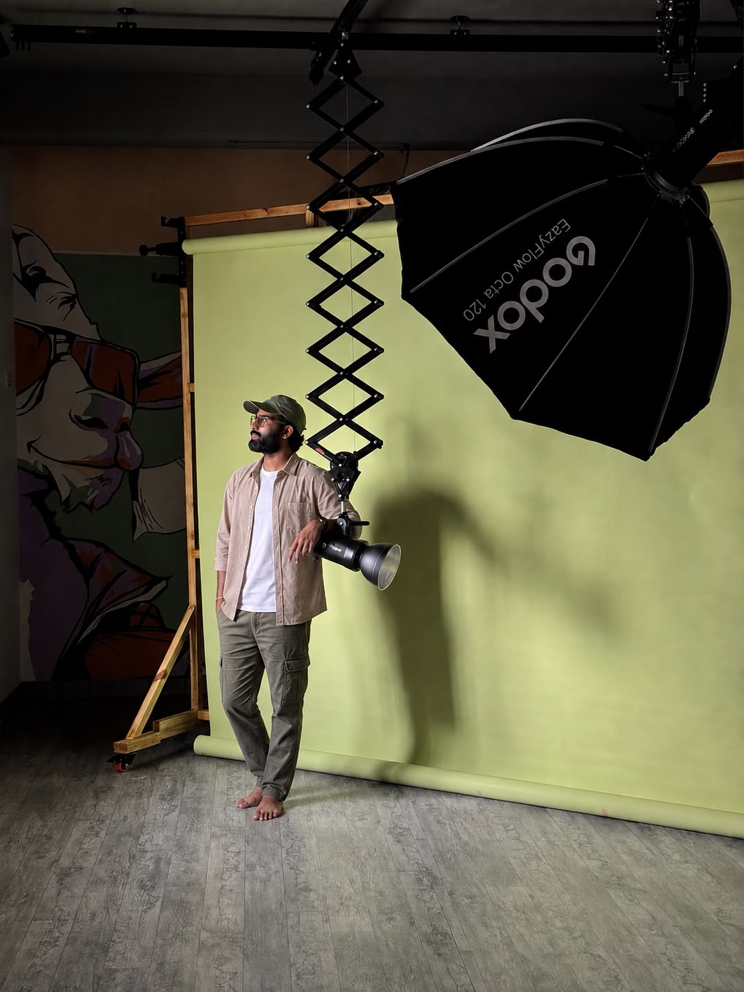 A photographer working with studio lighting and a green backdrop at YNotFramez Studios